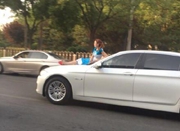 北京一女子坐在轿车引擎盖上行驶而过 惊呆网友